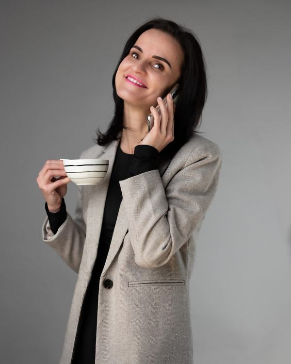 Agentka nieruchomości z filiżanką kawy i telefonem, kadr lifestyle w studiu