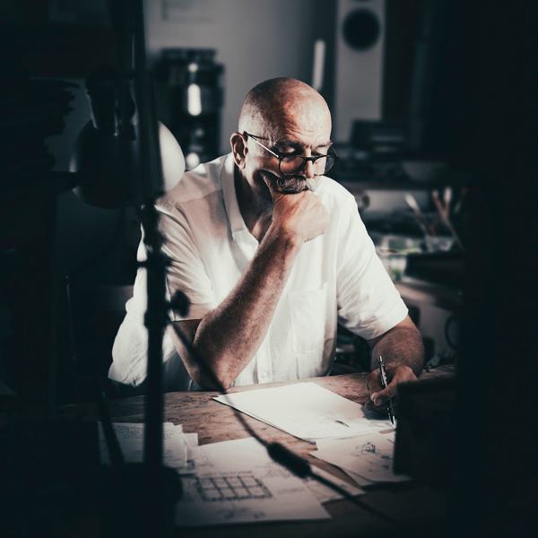Artysta w białej koszuli zamyślony przy biurku w pracowni, portret w pracowni