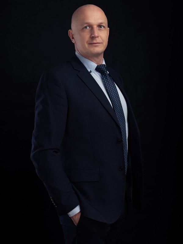 Menedżer w garniturze z dłonią w kieszeni, portret wizerunkowy na czarnym tle