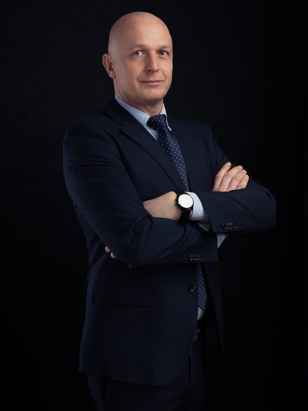 Dyrektor w granatowym garniturze z rękami skrzyżowanymi, portret biznesowy na czarnym tle