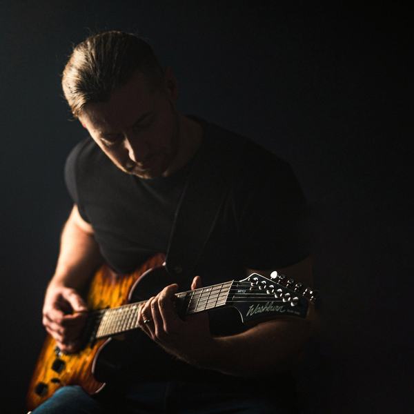 Gitarzysta z gitarą w odcieniach bursztynu, portret muzyka, studio w Katowicach