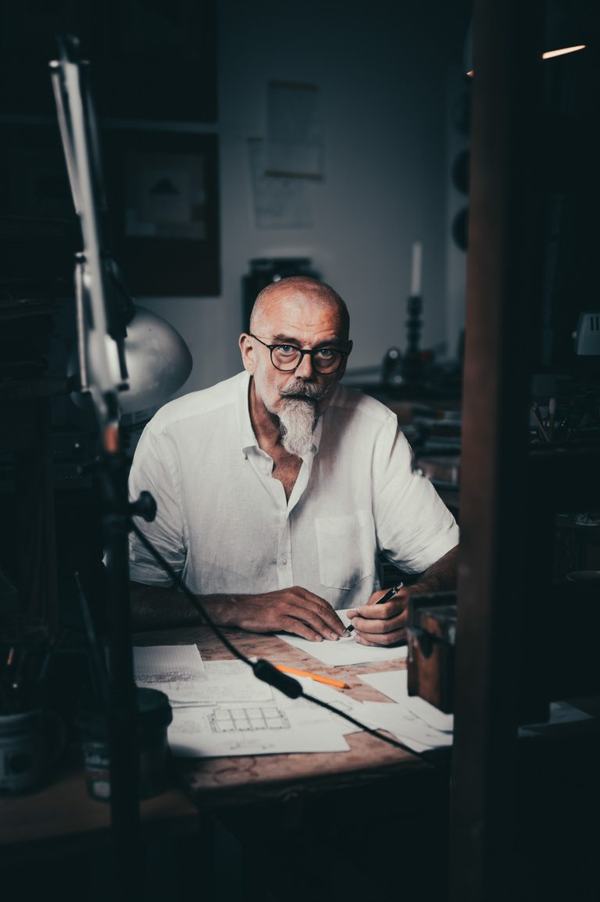 Portret artystyczny: mężczyzna w okularach przy biurku z lampą w pracowni