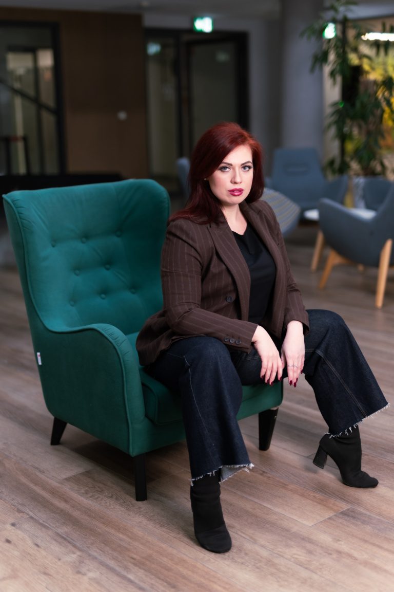Portret biznesowy prawniczki w brązowej marynarce na zielonym fotelu w holu biurowca, Katowice