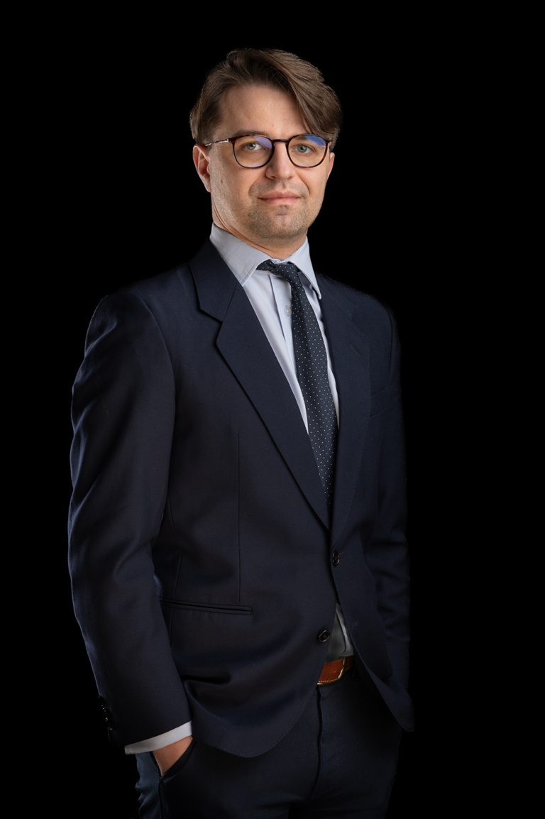 Portret biznesowy mężczyzny w okularach i garniturze na ciemnym tle