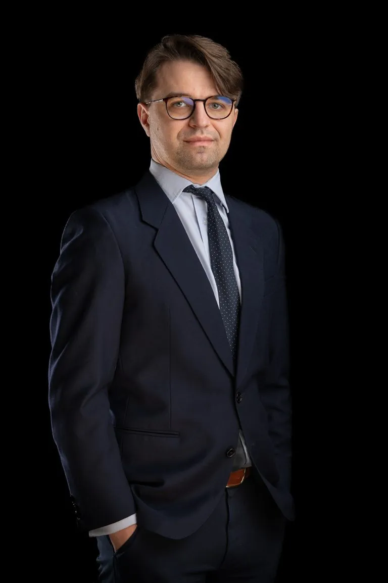 Portret biznesowy mężczyzny w okularach i garniturze na ciemnym tle