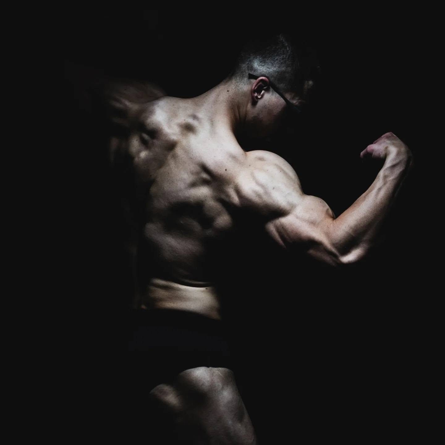 Sesja fitness trenera personalnego: napięte mięśnie w świetle konturowym na ciemnym tle
